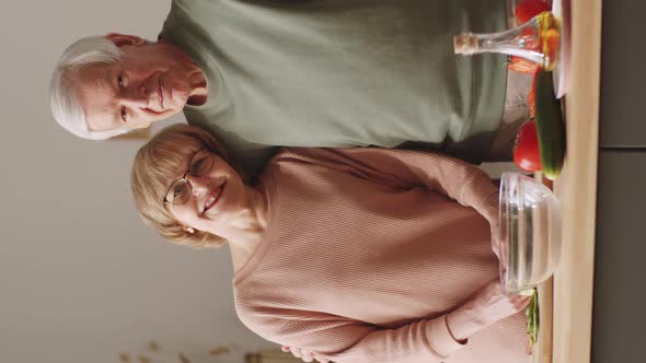 Romantic Senior Couple Cooking in Kitchen and Smiling at Camera alt