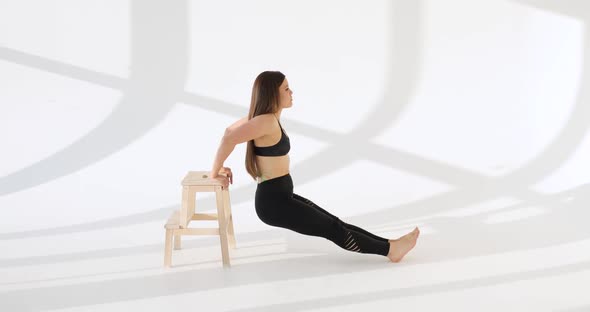 Side View of Young Caucasian Woman Working Out Doing Exercises in a White Studio alt
