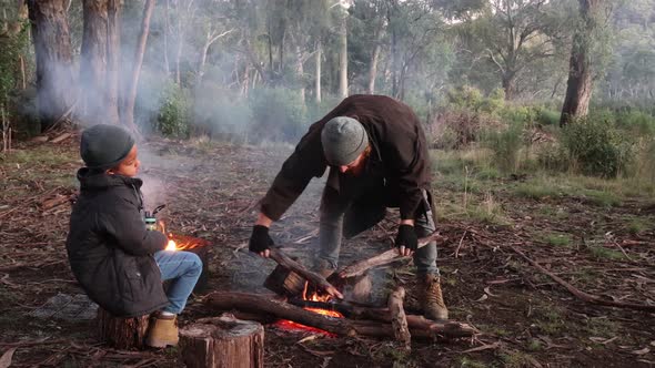 A bushman and a son create a fire in the cold winter of Australia alt