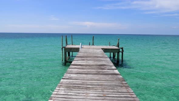 A T shape pier facing the open ocean, blue skies, green ocean alt