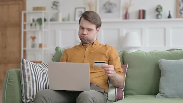 Young Man with Unsuccessful Online Payment on Laptop on Sofa alt