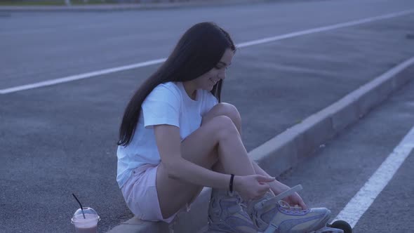 Charming Young Woman Putting on Rollers at Dusk. Portrait of Beautiful Caucasian Sportswoman Ejoying alt