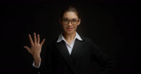Asian Woman in Glasses Smiling and Shows Five Fingers with Her Right Hand