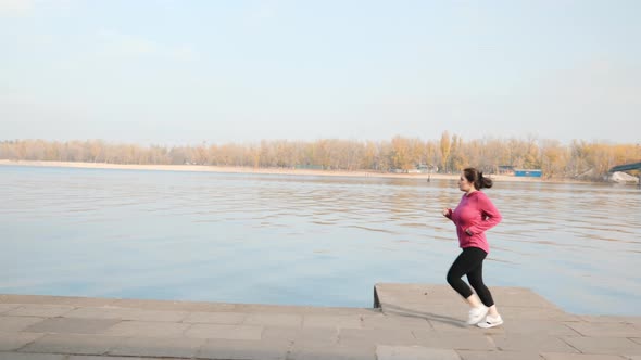 Chubby young woman running in city promenade as a part of weight loss program. Running concept alt