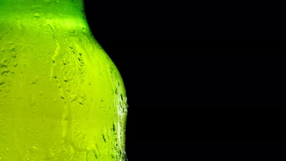 A Bottle of Cold Beer Slowly Rotates Against a Dark Background