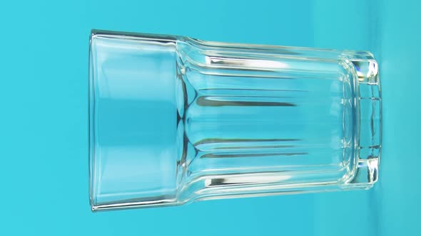 Vertical Video Closeup Shot of Milk Cold Beverage Drink Pooring Into Faceted Glass on Colored Blue