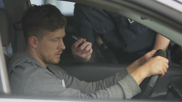 Police Officer Giving Alcohol Detection Device to Young Male Driver, Control alt