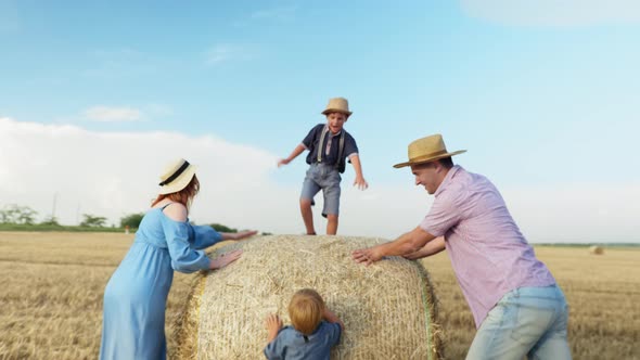 Parenting, Family Having Fun on Field of Riding Children on Haystack alt