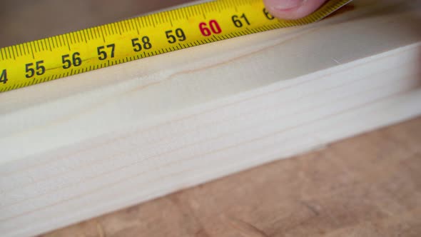 Yellow Ruler Tape Measure Measures a Wooden Bar Close Up Black Pencil Mark alt