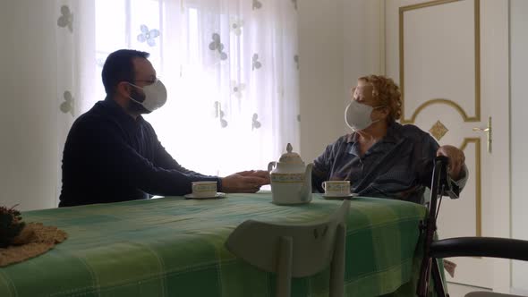 Elderly woman and young man talk while keeping distance and using masks because of covid-19.