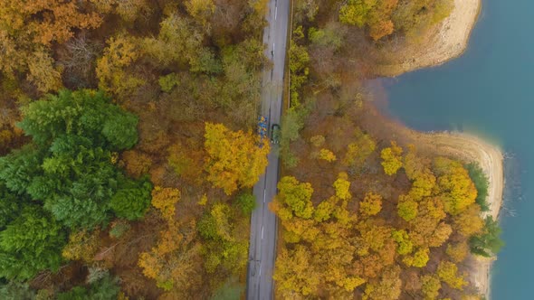 Top View of Car Passing a Transportation Truck or Van on Scenic Road in Golden Forest