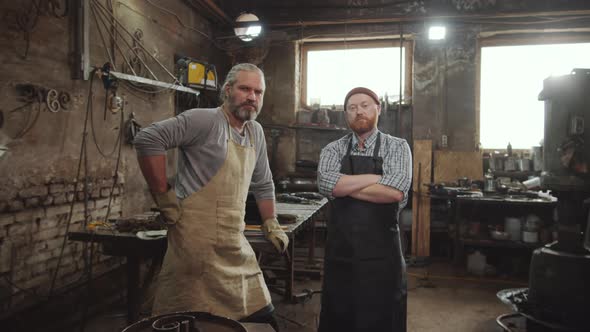 Two Blacksmiths Posing for Camera in Workshop alt