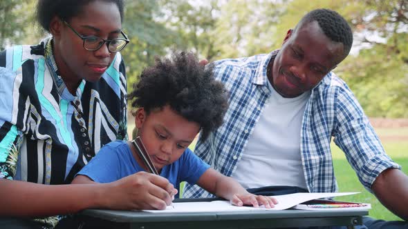 Happy African American family with son to sketching the tree in the park