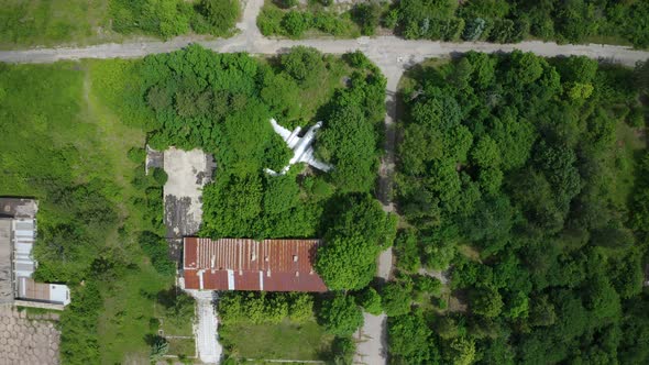 Abandoned old airplane in the middle of green field, aerial top down alt