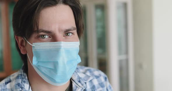 Portrait of Young Man Lowers Medical Mask and Looks Thoughtfully at Camera alt