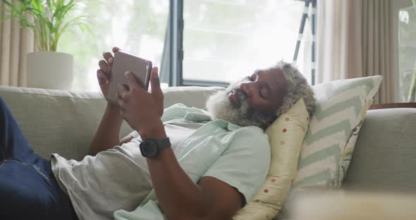 Video of sad african american senior man laying on sofa alt