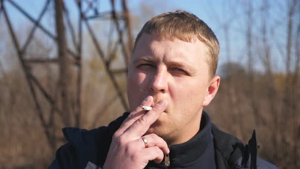Portrait of Adult Serious Man Looking Into Camera and Smoking Cigarette Outdoor alt