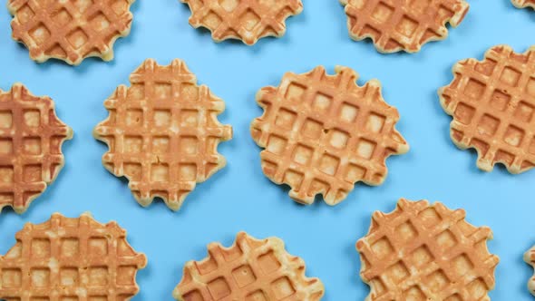 Rotating Background of Appetizing Sweet Waffles on a Blue Background alt