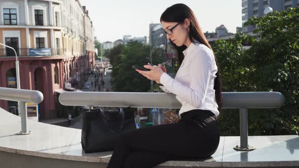 Business Woman Using Smartphone While Working on Go at Urban Street