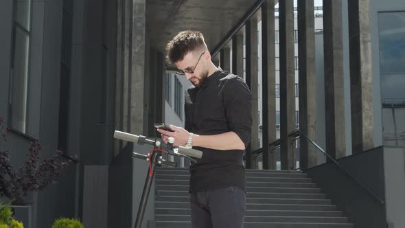 Electric Scooter Rental. A Man Who Approaches an Electric Scooter and Takes It for Rent. Ecological alt