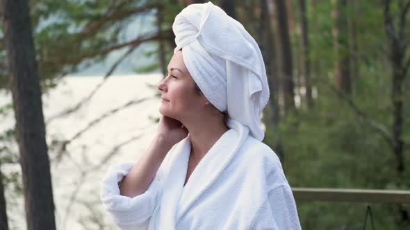 Young Woman in a Bathrobe and Towel on the Terrace on a Background of Mountains and Forest alt