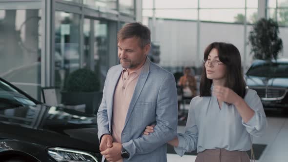 Smartly Dressed Couple Walking in Car Dealership alt