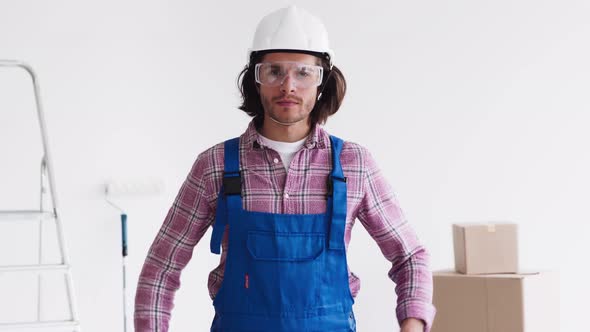 Confident Renovation Handyman Wearing Uniform with Protective Glasses and Helmet Looking at Camera alt