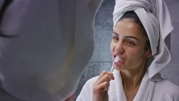 Portrait of Mixed Race Woman Brushing Her Teeth in Bathroom with Towel Wrapped on Her Head Wearing