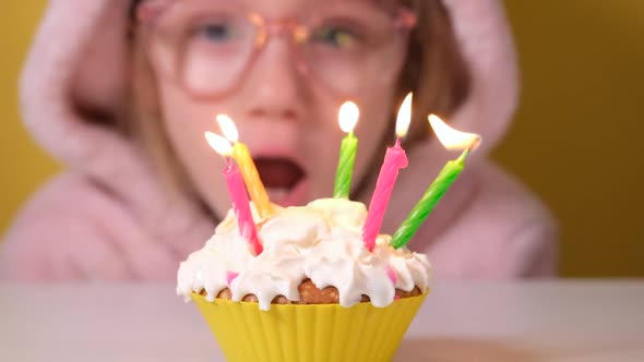 Happy Child Girl in Pink Overalls Blows Out Five Candles on Birthday Cake at Party