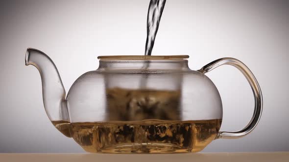Leaves of Green Tea Are Brewed in Teapot, White Background alt