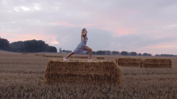 A Female Blonde Model Stretching on Top Of a Haystack alt