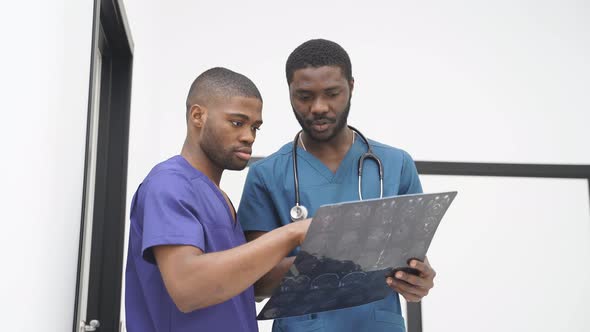 Two African American Male Colleagues Doctors Working Together Discussing and Examining Xray CT of