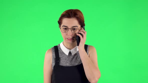 Portrait of Funny Girl in Round Glasses Is Angrily Talking for Mobile Phone. Green Screen alt