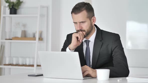 Pensive Businessman Thinking and Working on Laptop alt