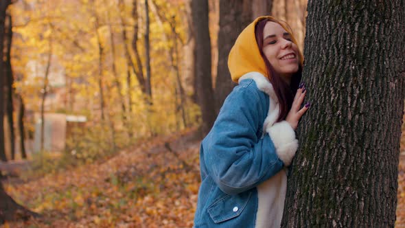 Young Woman Hugs Tree in Autumn Forest alt