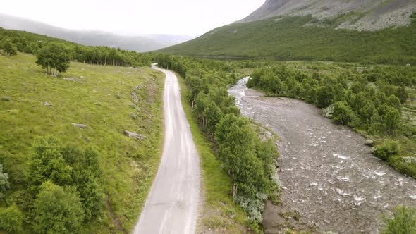 Black Car Travelling On The Mountain Road With Stream And Lush Green Trees In Hydalen Valley, Hemsed alt