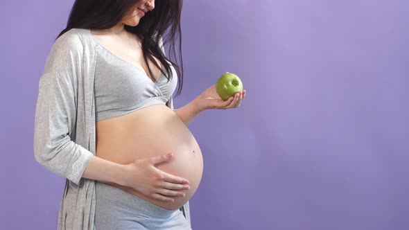 Pregnant Slim Woman with Big Belly Holding Apple Isolated Over Blue Wall alt