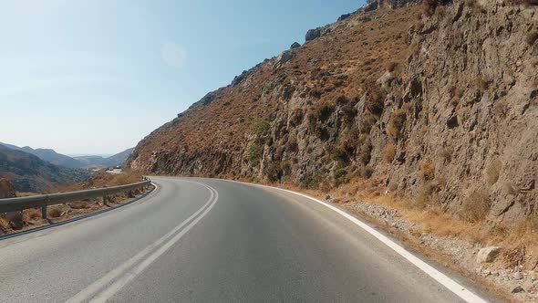 POV Driving a car on curvy asphalt road with rocky mountains near Grand Canyon. Blue sky with white alt