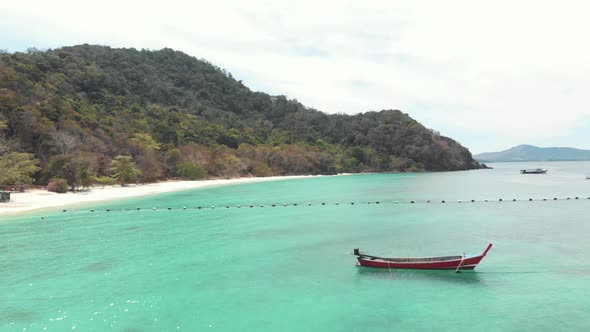 Long-tail fishing boat resting above scenic turquoise shallow sea in Banana Beach in Coral Island alt