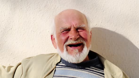 Old happy grandfather with white beard laughs, Slow motion