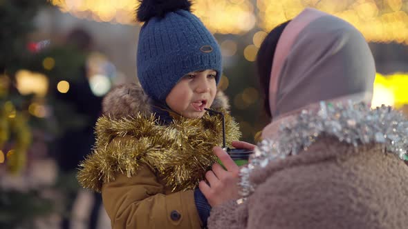 Cute Excited Son Talking with Mother on City Square Decorated for Christmas alt