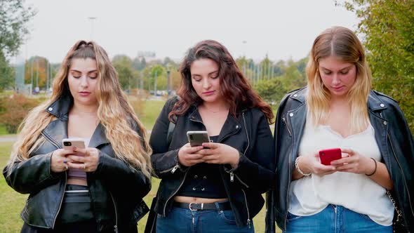 Portrait of three young women with smart phones outdoors, Italy