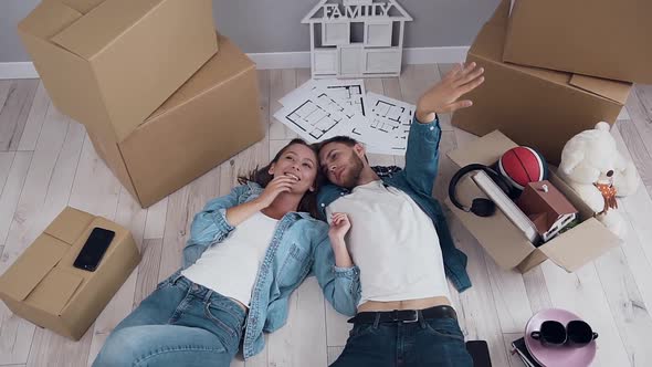 Happy Couple Husband and wife Lying on Floor in New Apartment Talking alt
