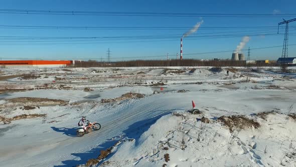 a motorcyclist performs stunts on a winter track alt