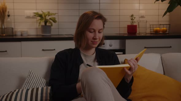 Closeup of a Woman Writing By Hand in a Yellow Notepad in a Homely Atmosphere alt