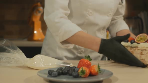 the Pastry Chef Prepares a Meringue Roll with Cream and Fruit and Takes Dessert To the Client alt