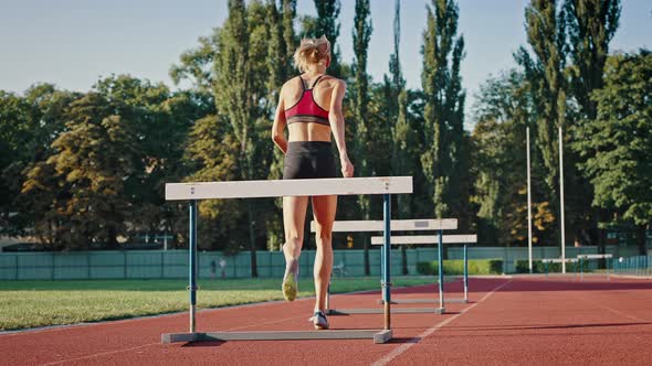 Low Angle Shot of a Professional Sportswoman Running a Distance with Obstacles alt