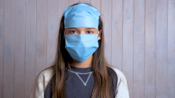 Portrait of a beautiful dark haired school girl wearing protective medical face mask on forehead alt