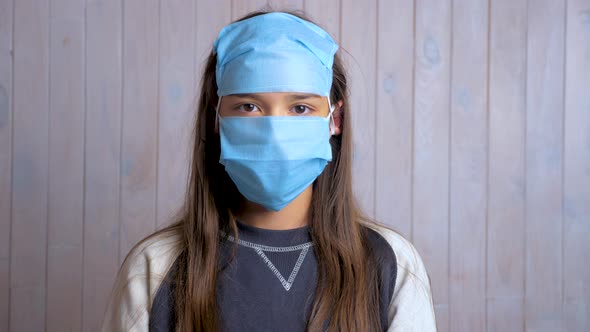 Portrait of a beautiful dark haired school girl wearing protective medical face mask on forehead