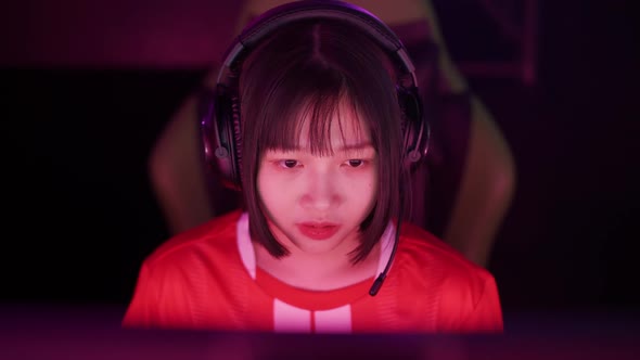 Portrait of an Asian Female Gamer in Headphones Plays a Video Game Cyber Sportsman at the Game alt